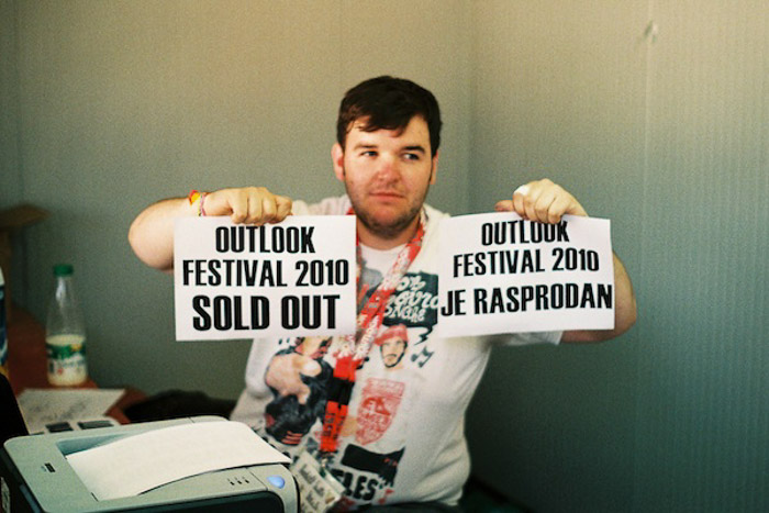 一名男子举着两张宣传节日的印刷标语——摄影天平，票已售罄