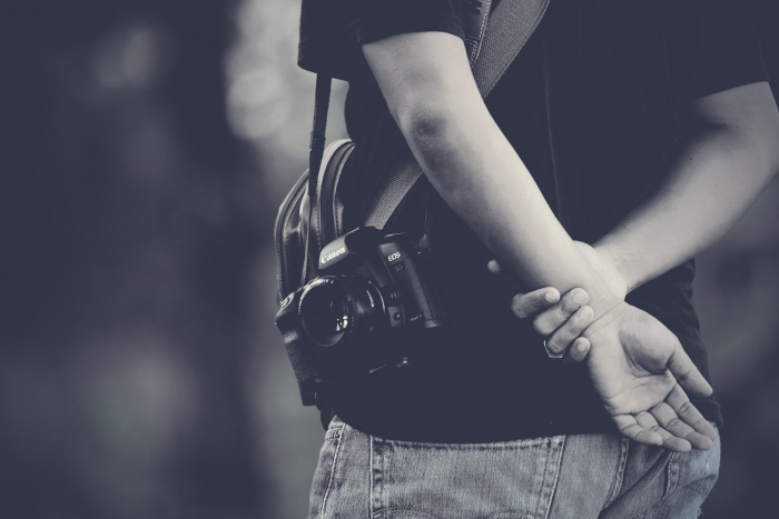 一个黑色和白色的特写镜头，一个男人与一个不显眼的50mm镜头拍摄偷拍的街头照片