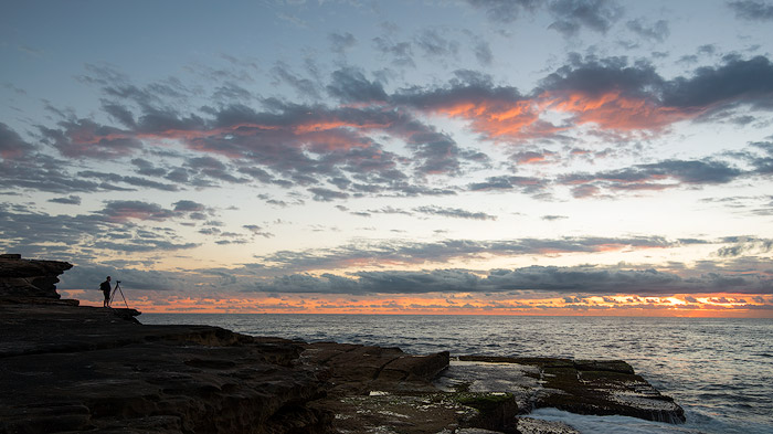 采取日出摄影的一位摄影师在岩石海岸