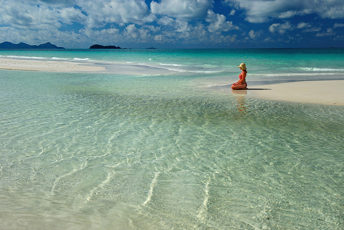 一个女孩跪在海滩海景在白天