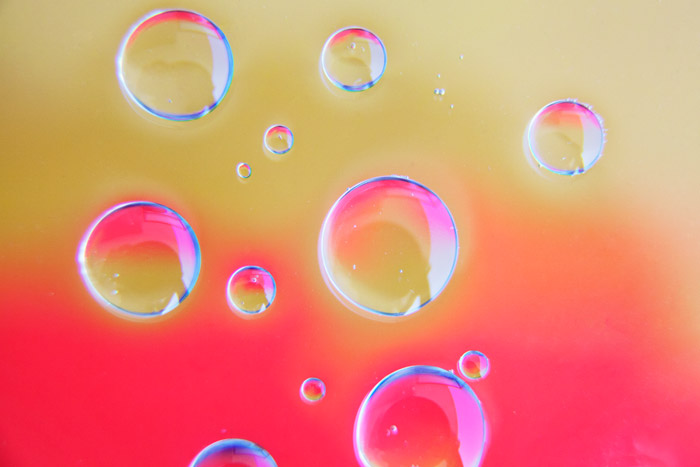明亮的粉色和沙质背景，13个清晰的泡泡，这是用油和水拍摄的