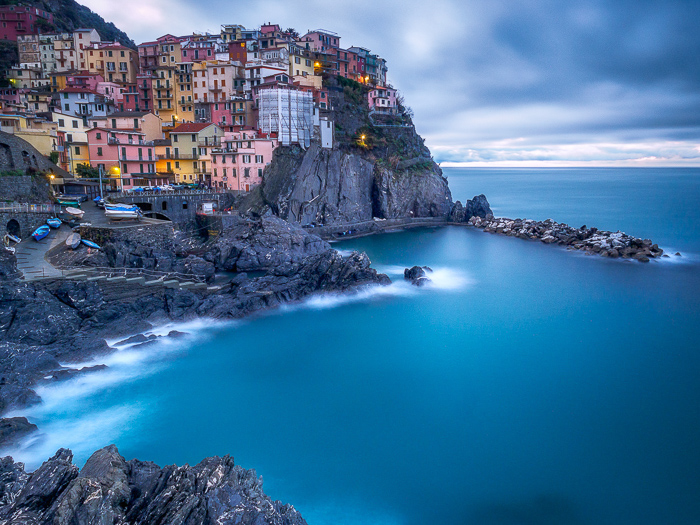 Long-exposure photo of a coastal town and seascape in Manarola at sunset.