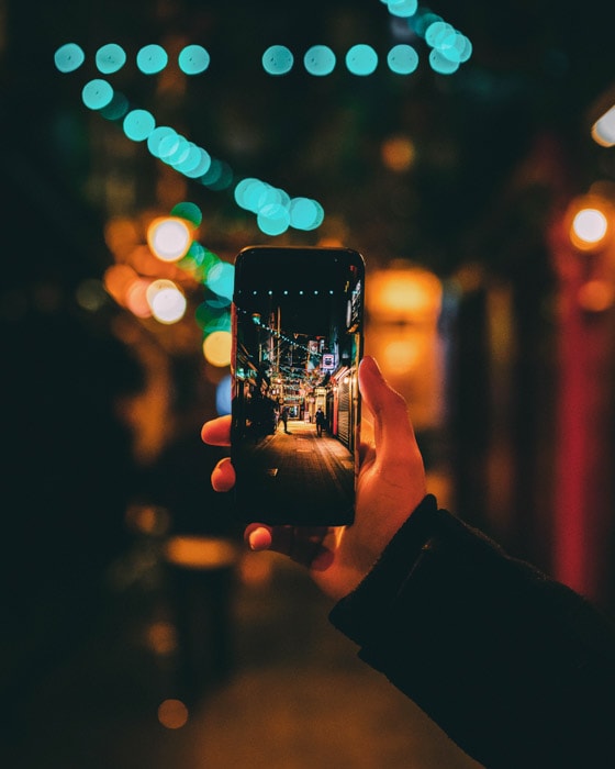手握智能手机，用宽景深和浅景深相结合，自然地为夜街照片相框