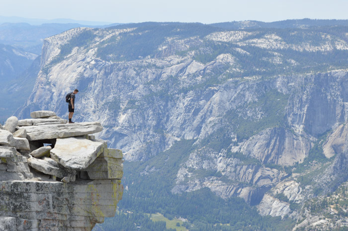 站立在一个峭壁边缘的一个人与在他后的令人印象深刻的山风景展示在摄影的大小重量平衡