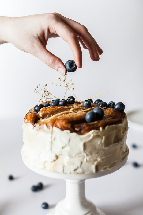 美味的食物照片，手把蓝莓放在蛋糕上的白色背景，用微距镜头拍摄的静物摄影