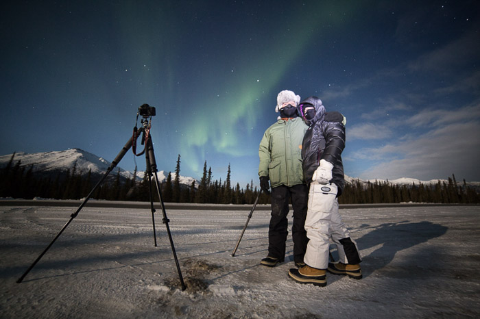 两个摄影师照片有照相机和三脚架射击北极光的。冬季摄影。