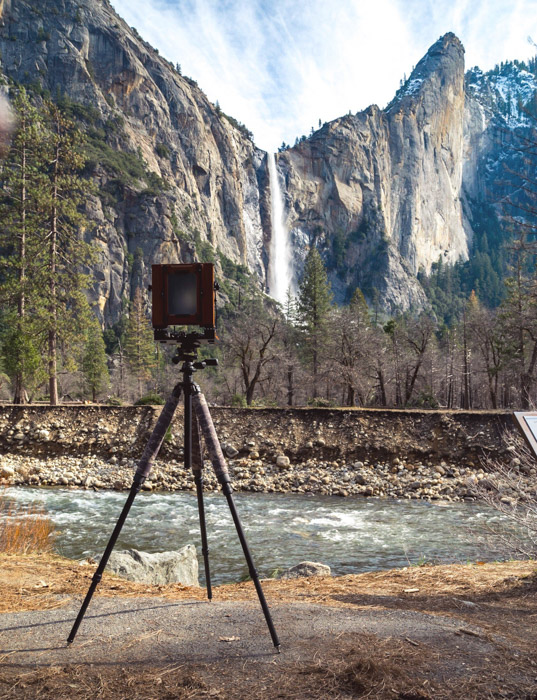 有胶片照相机的三脚架指向令人惊叹的山地景观