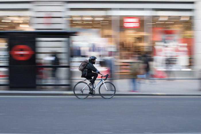 在城市骑自行车的人，背景是由于使用慢速快门速度导致的创造性模糊