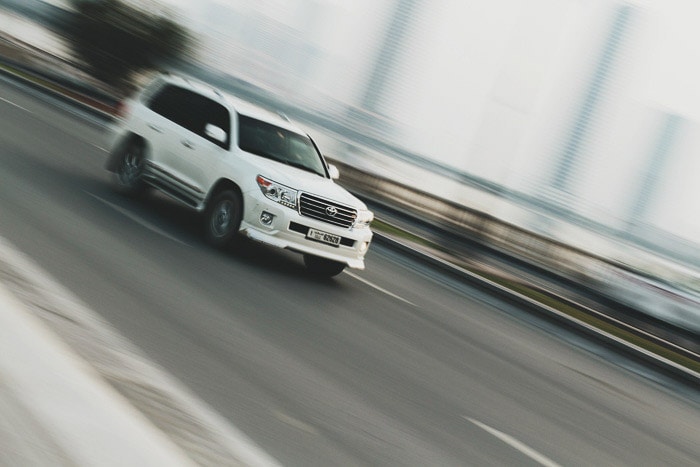 一辆白色的汽车驾驶，背景是一种创造性的模糊，展示了快门速度及其用途
