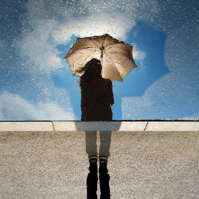 创意雨景照片，一个人撑着伞，倒映在雨点溅起的窗户上