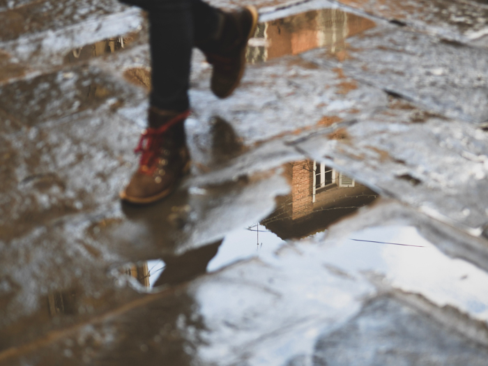 一个人的脚在街上走过水坑的大气雨照片