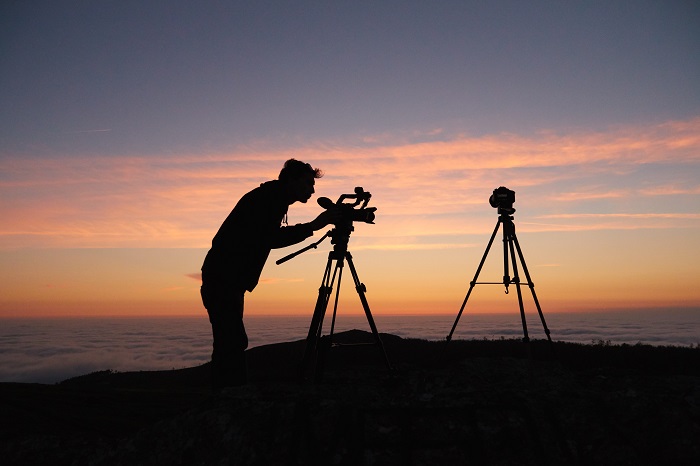 日落时分，一个摄影师在三脚架上用单反相机拍摄的剪影