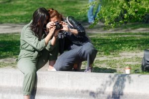两个妇女在看一个dslr照相机的公园