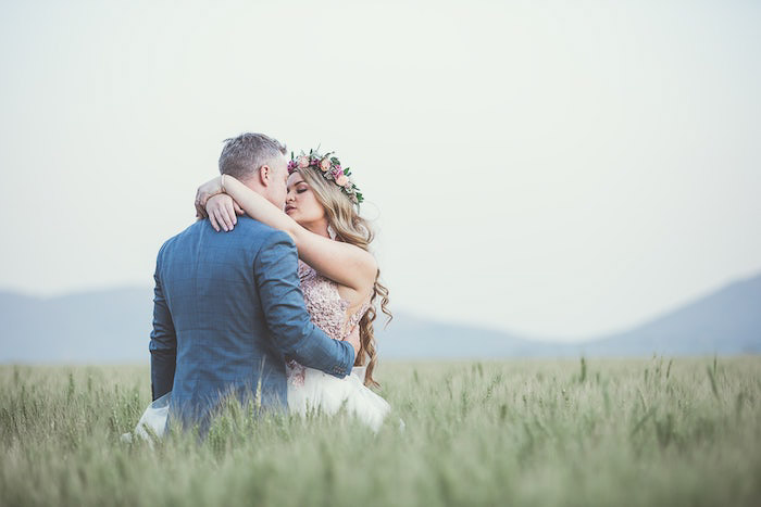 一对新婚夫妇在草丛中拥抱的照片——专业摄影