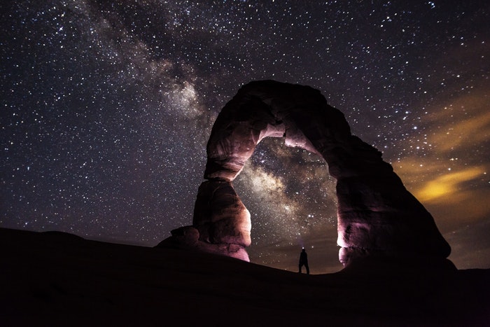与一个人的一个惊人的夜摄影图象在石曲拱和满天星斗的天空下