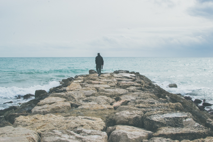 明亮和通风的照片，一个人走向大海上的岩石码头-焦点摄影