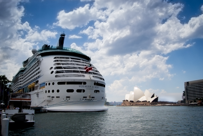 一艘大渡船停靠在一个港口，后面是悉尼歌剧院
