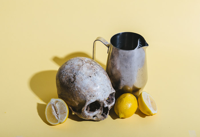 淡黄色背景上的骷髅、柠檬和花瓶的静物画——摄影中的象征意义