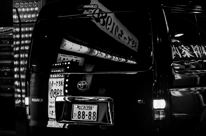 黑色和白色的图像，后面的黑色货车与反射从周围的建筑物