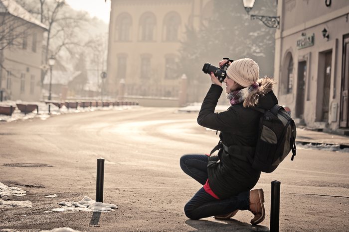一位女摄影师正在用单反相机拍摄街景