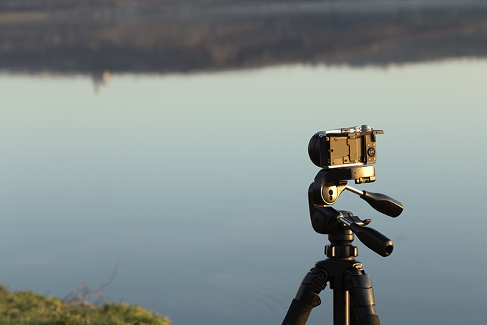 三脚架上的相机以湖为背景。