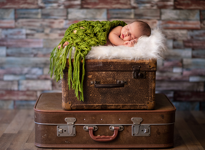 刚出生的小婴儿睡在乡下的行李箱上