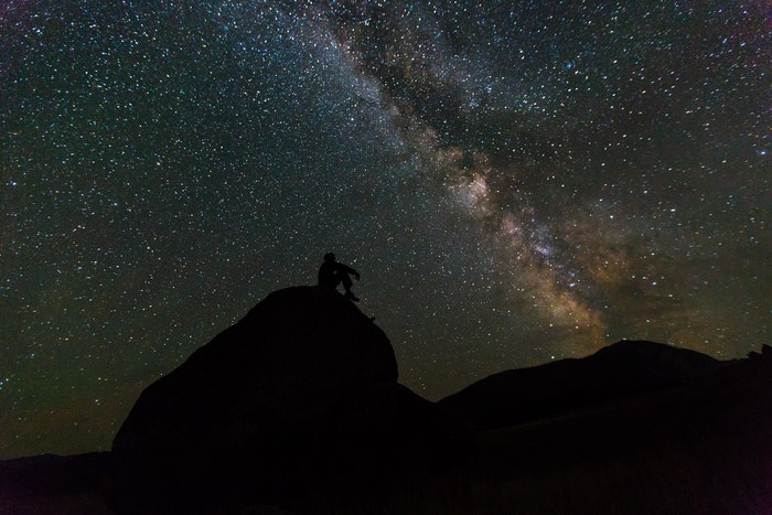 惊人的天线图射击了一个人的剪影在一块岩石的在一颗星填装的天空前面